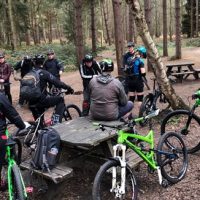 People stood and sat around with bikes in Sherwood Forest.