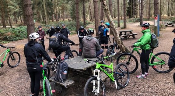 People stood and sat around with bikes in Sherwood Forest.