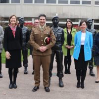 A group of people stand with with statues of soldiers.