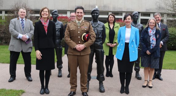 A group of people stand with with statues of soldiers.