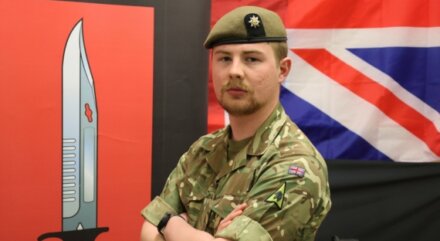 Army Reservist in uniform stands with arms crossed, looking confidently into the camera.
